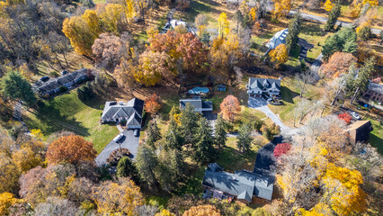 High-resolution aerial of suburban Newburgh NY showing rooftops, trees, and fall landscapes. Autumn colors pop as roads divide quiet residential streets in scenic symmetry and order.