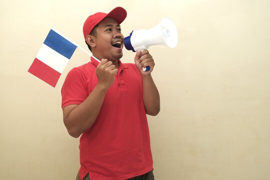 Southeast Asian man holding French flag and megaphone, promoting visa, scholarship, or study abroad opportunities in Italy; isolated with copy space for advertisement.