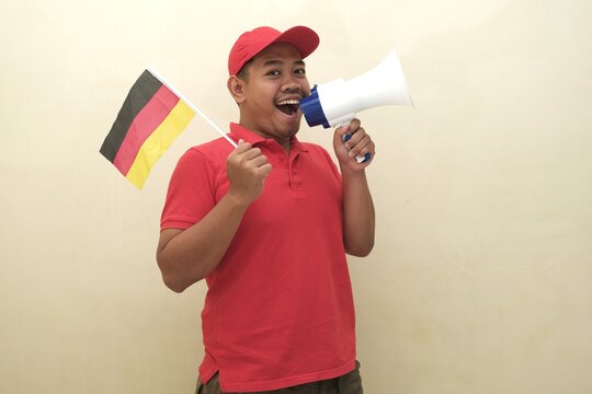 Southeast Asian man holding German flag and megaphone, promoting visa, scholarship, or study abroad opportunities in Italy; isolated with copy space for advertisement.