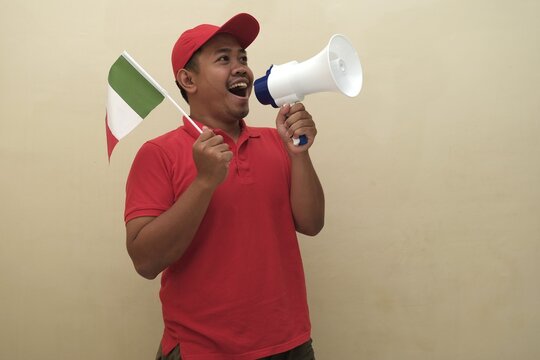 Southeast Asian man holding Italian flag and megaphone, promoting visa, scholarship, or study abroad opportunities in Italy; isolated with copy space for advertisement. - Powered by Adobe
