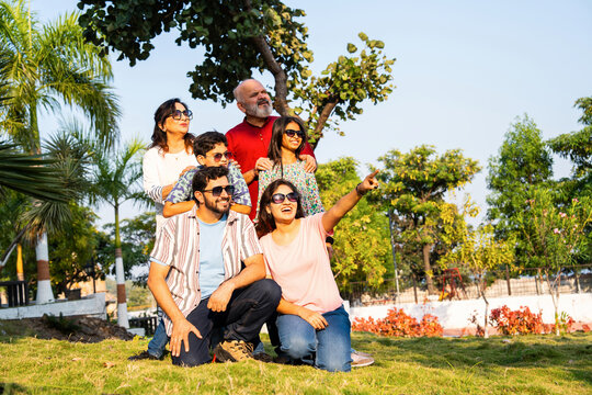 Indian family on lawn pointing ahead together, smiling and promoting an outdoor advertising idea