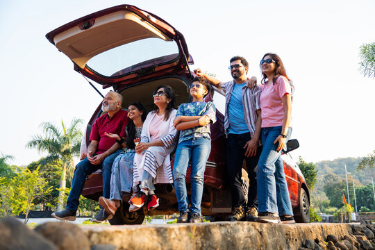 Indian family sitting in car dicky outdoors, enjoying laughter and bonding before a picnic