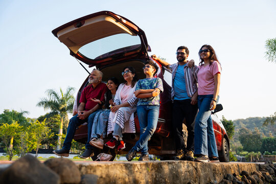 Indian family sitting in car dicky outdoors, enjoying laughter and bonding before a picnic