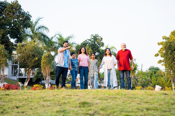 Obraz premium Indian family walking through green farm fields enjoying nature and joyful family togetherness