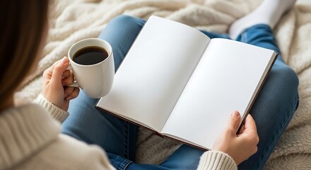 Person relaxing at home, holding an open blank book with empty pages and a warm cup of coffee on a cozy blanket