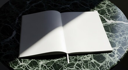 Open blank notebook with white pages resting on a dark green marble table, illuminated by natural light and shadow, ready for creativity