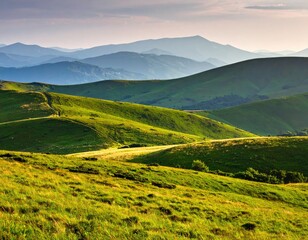 Obraz premium Rolling green hills under a vast sky show a winding path.