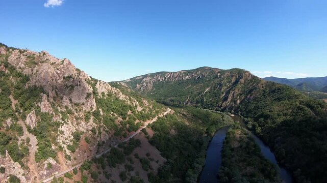 High-altitude drone flight rising forward with a panoramic rotation, revealing sharp cliffs, rock niches, and vertical walls, then moving toward the iconic Arda River bend