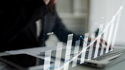 A business professional analyzes financial performance using a laptop, featuring a transparent graph overlay in a modern office environment, embodying data-driven decision-making. Copula