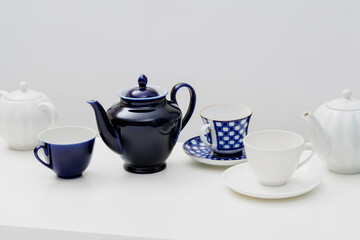 Ceramic teaware. Teapot, cup, and saucer on a white table. Light background.