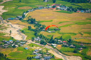 Colorful paragliding athletes on golden rice terraces in Khau Pha pass, Mu Cang Chai town near Sapa...