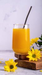 Refreshing Citrus Drink in a Clear Glass with Straw Surrounded by Bright Yellow Flowers on a Wooden Board