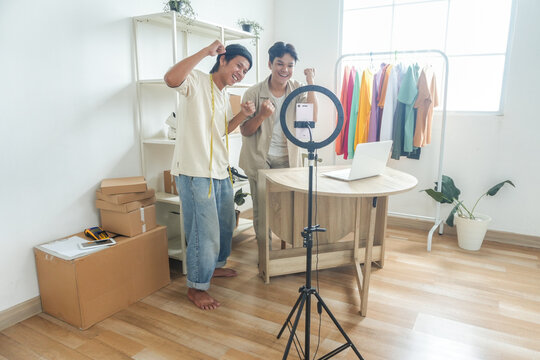 Excited Entrepreneurs Celebrating Online Sales Success With Live Stream Setup in Vibrant Home Studio