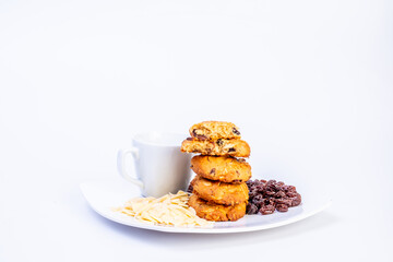 Delicious homemade almond and raisin cookies served with a cup of coffee on a white plate. Close-up of cookies with sliced almonds and raisins