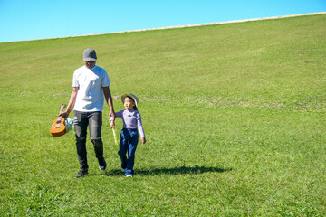 Father and Daughter Enjoying Sunny Day Out, Strolling Across Large Expanse of Green