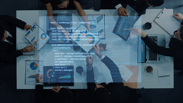 A diverse business team collaborates in an office setting, analyzing data visualizations on digital devices, engaged in strategic discussions and planning. Trope