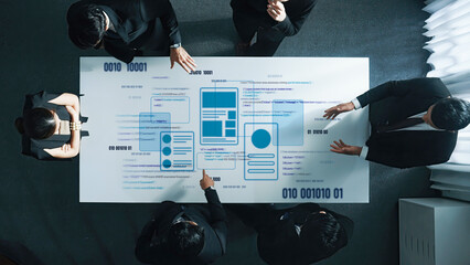 A group of business professionals collaborates around a conference table, engaging with digital interface elements and data visualizations for strategic planning. Trope