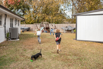 siblings playing flag football in backyard with dachshund playing © Cavan