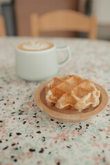 Belgian waffle and latte on terrazzo table with soft background