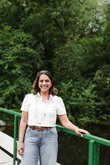 Smiling woman leans casually on bridge railing