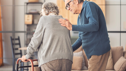 Fototapeta premium An elderly couple helps each other while using a walking frame