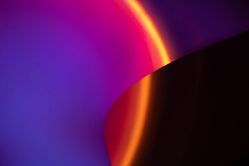 Abstract gradient of vibrant purple and pink colors with a bright orange glow curving across a dark background