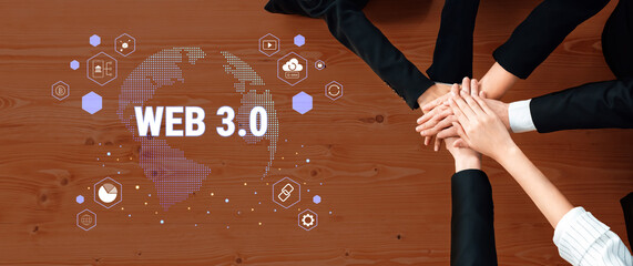 A diverse business team collaborates on Web 3.0 innovations, showcasing unity with hands stacked on a surface, surrounded by visual graphics representing global technology themes. Trope