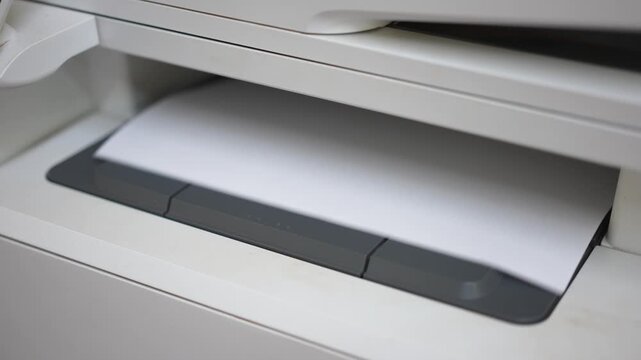Many of A4 white paper were printing out from photocopy machine in fast motion, Close-up with selective focus.