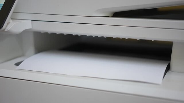 Many of A4 white paper were printing out from photocopy machine in fast motion, Close-up with selective focus.