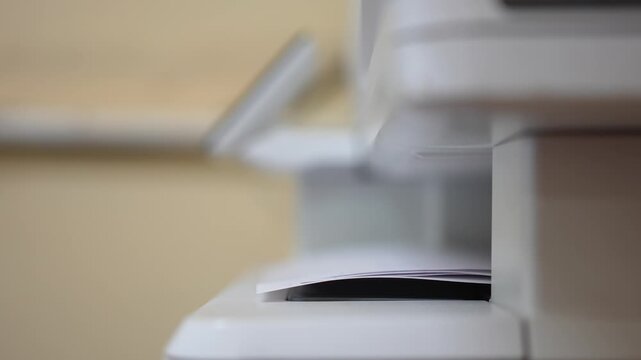 Many of A4 white paper were printing out from photocopy machine in fast motion, Close-up with selective focus.