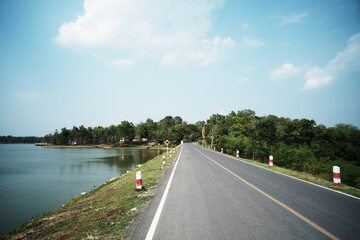 Country road by reservoir to the mountain natural landscape and tropical forest of rural in Thailand
