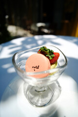 A glass of Green tea ice cream with orange macarons and strawberries on topping on white table outdoor