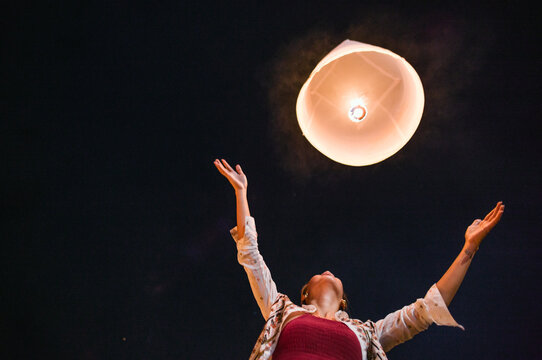Asian woman releasing a paper lantern during Yi Peng festival, Chiang Mai, Thailand