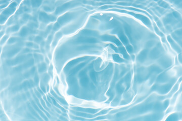 Blue water with ripples on the surface. Defocus blurred transparent blue colored clear calm water surface texture with splashes and bubbles. Water waves with shining pattern texture background.