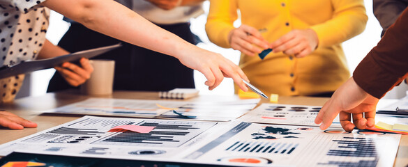 A dynamic office meeting scene showing a diverse group of professionals analyzing data reports and charts, fostering collaboration and innovative ideas for effective decision-making. SACTR