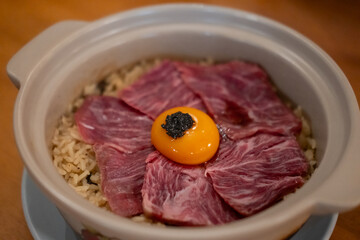 Beef fat fried rice in a bowl, with sliced meat and egg yolk on top