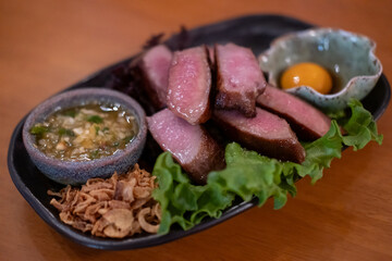 Grilled beef tongue served on plate with pickled egg yolk and sauce