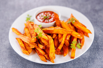 crispy sweet potato fries with spicy tomato sauce on white plate