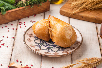 Uzbek samsa pastry served on a traditional patterned plate with rustic ingredients around