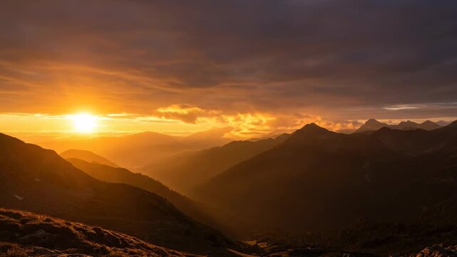 A breathtaking nature landscape at sunset and sunrise features orange clouds over mountain peaks and desert hills during a misty morning dawn