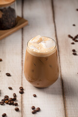 Refreshing iced coffee served with creamy foam ice cubes and aromatic spices on rustic table
