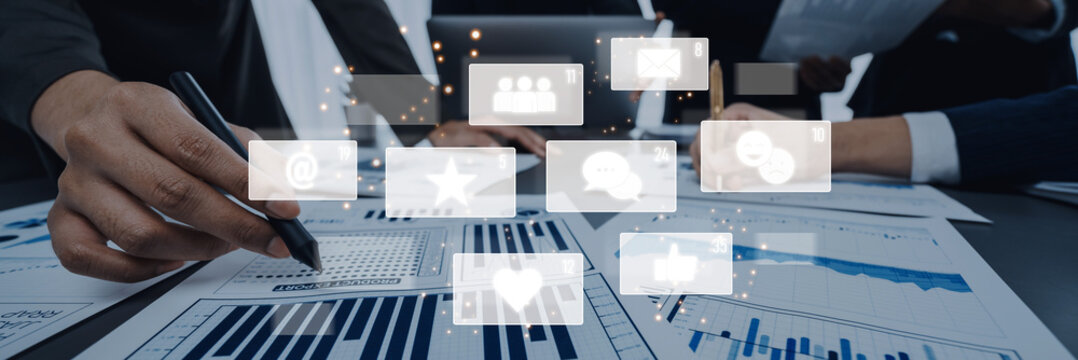 Hands work on reports while digital icons represent social media engagement. Explore themes of teamwork, data analysis, and communication in a professional environment. Trope