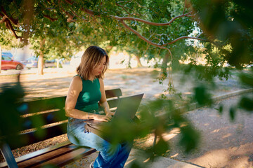 Woman working on laptop in park remote studying