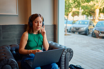 Woman teleworking with laptop and headphones in cafe