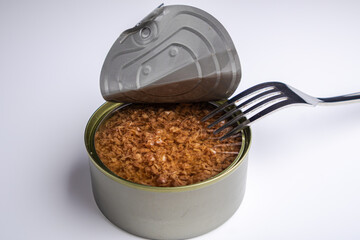 Can of chopped tuna in oil with a fork on a white background