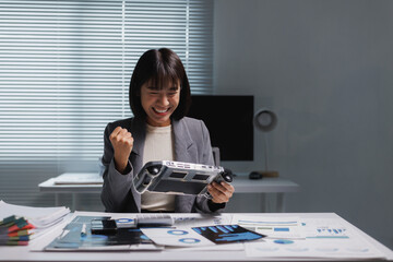 Young businesswoman enjoying handheld video game winning at office