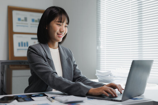 Young financial professional analyzing business data smiling at desk - Powered by Adobe