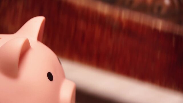 A man's hand makes a bill on vintage wooden bills against a piggy bank background.