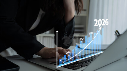 A business professional examines a laptop screen displaying a futuristic growth graph, depicting trends and projections for 2023 to 2026 in a sleek office environment. Tessel