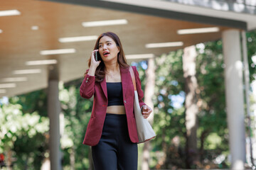 Young woman walking and talking on smartphone feeling surprised
